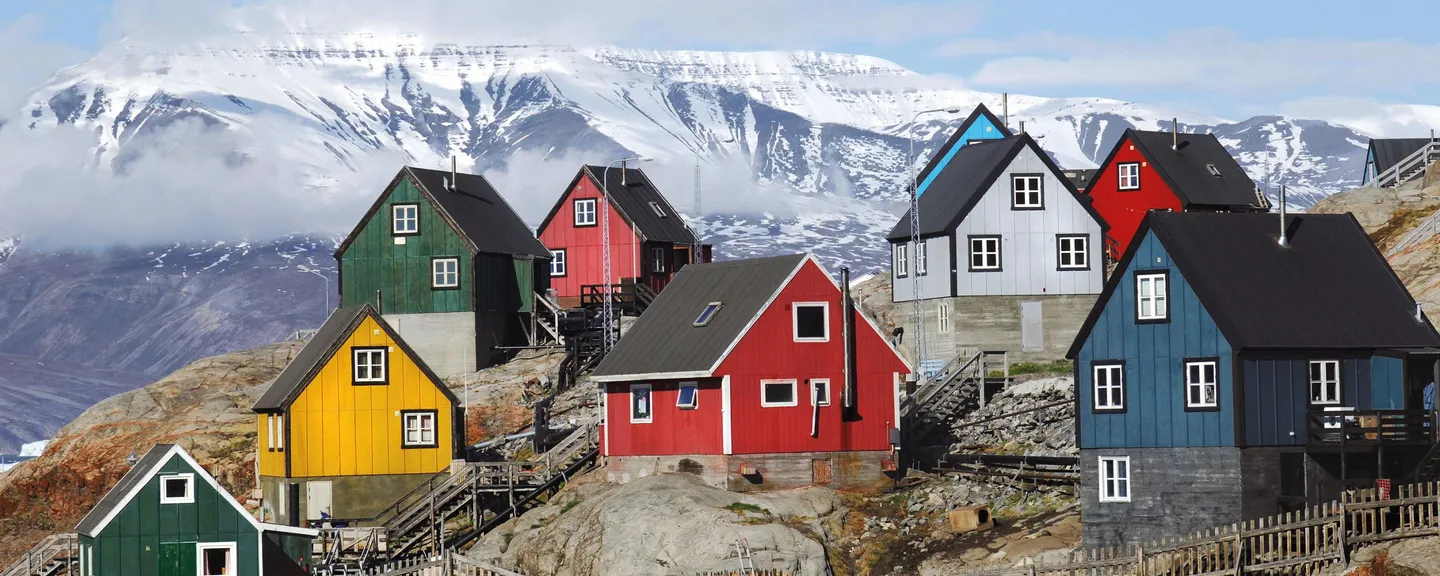 Colorful houses on a hillside with snowy mountains in the background