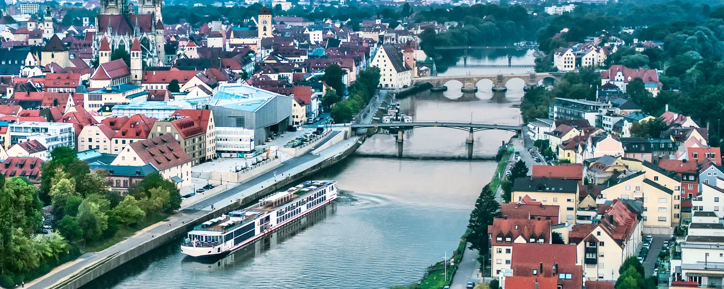 A river cruise ship sailing on a river that goes through a European city