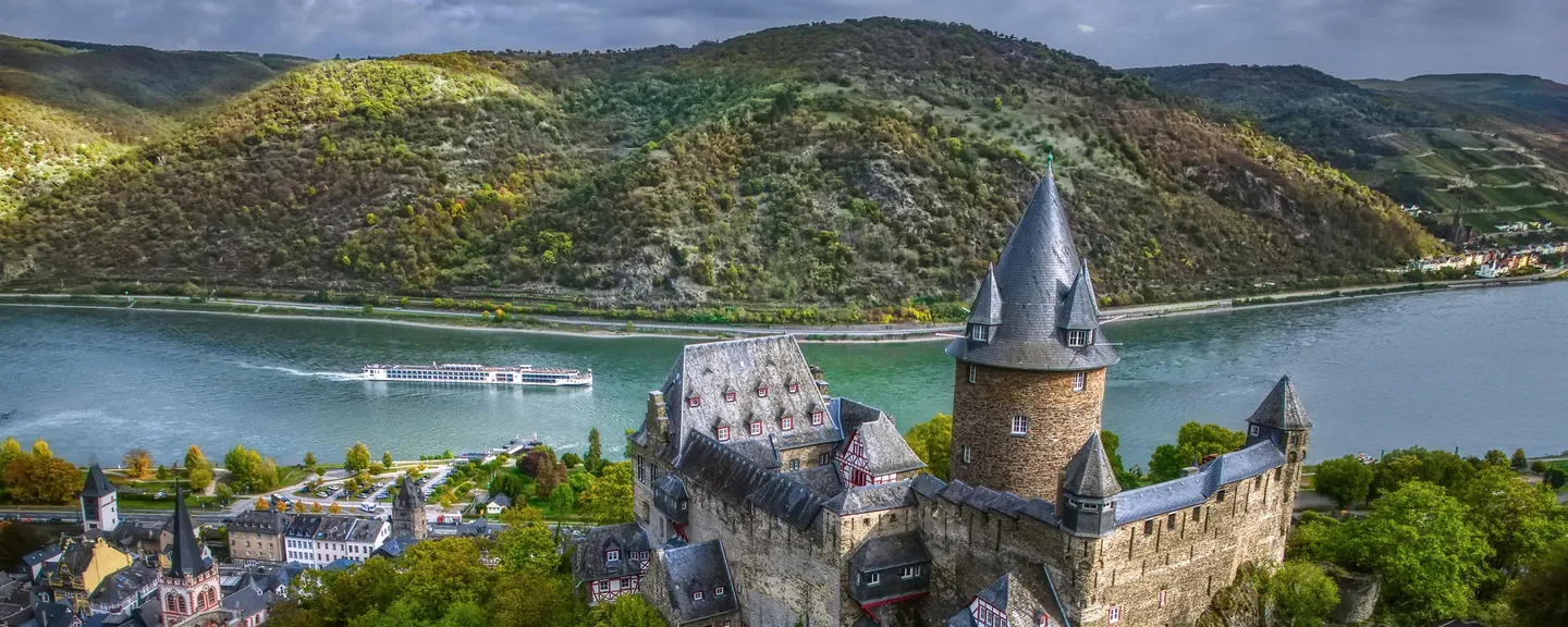 A Viking longship sailing on a river near a castle