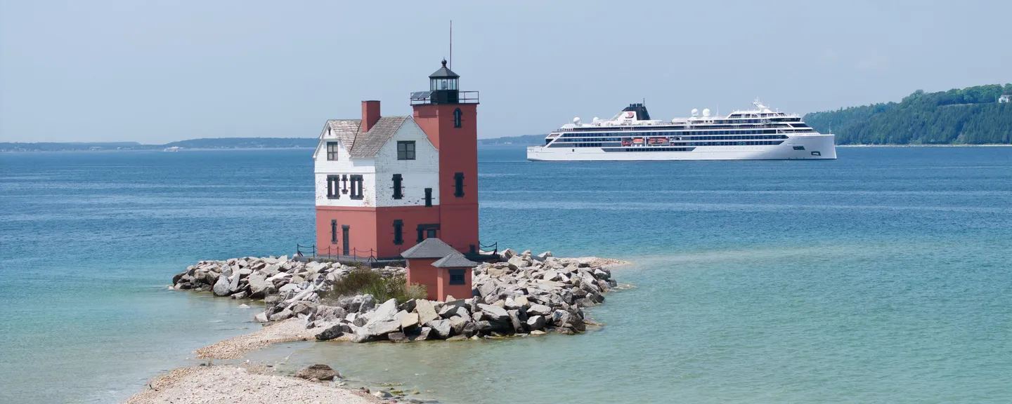 A lighthouse with a Viking expedition sailing on the water in the background