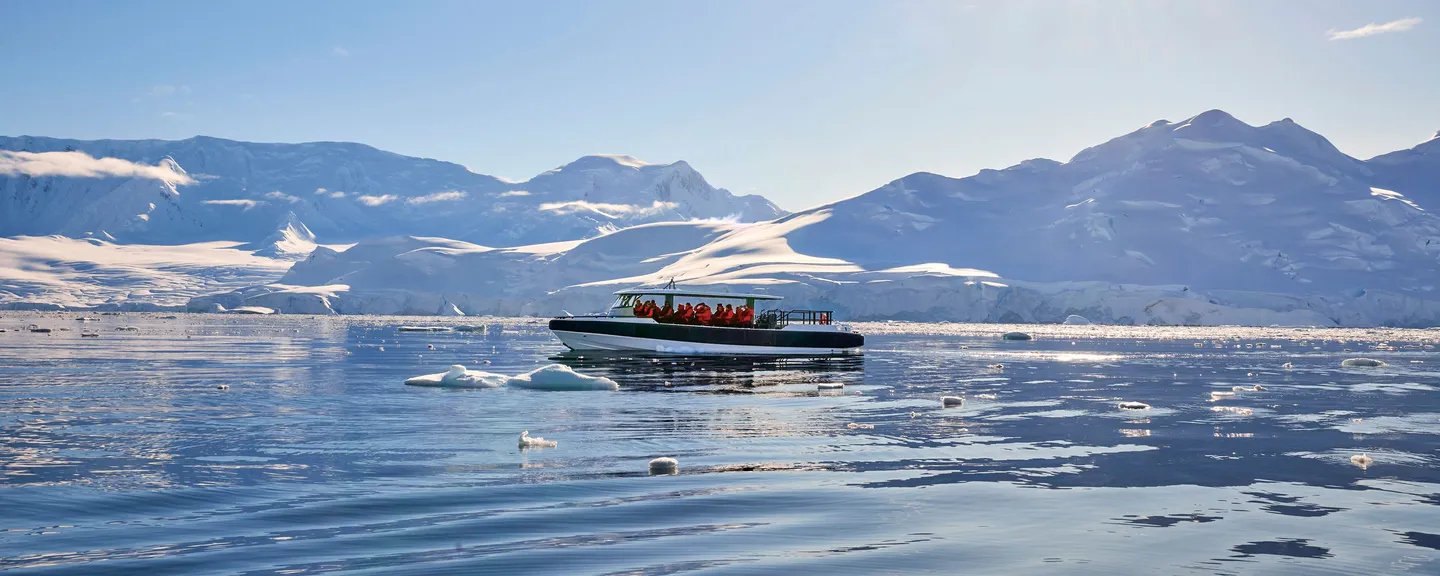 A special operations boat sailing on the water in front of a snowy landscape