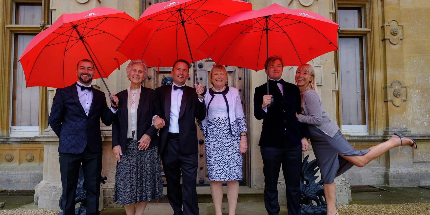 Group with red umbrellas at formal event