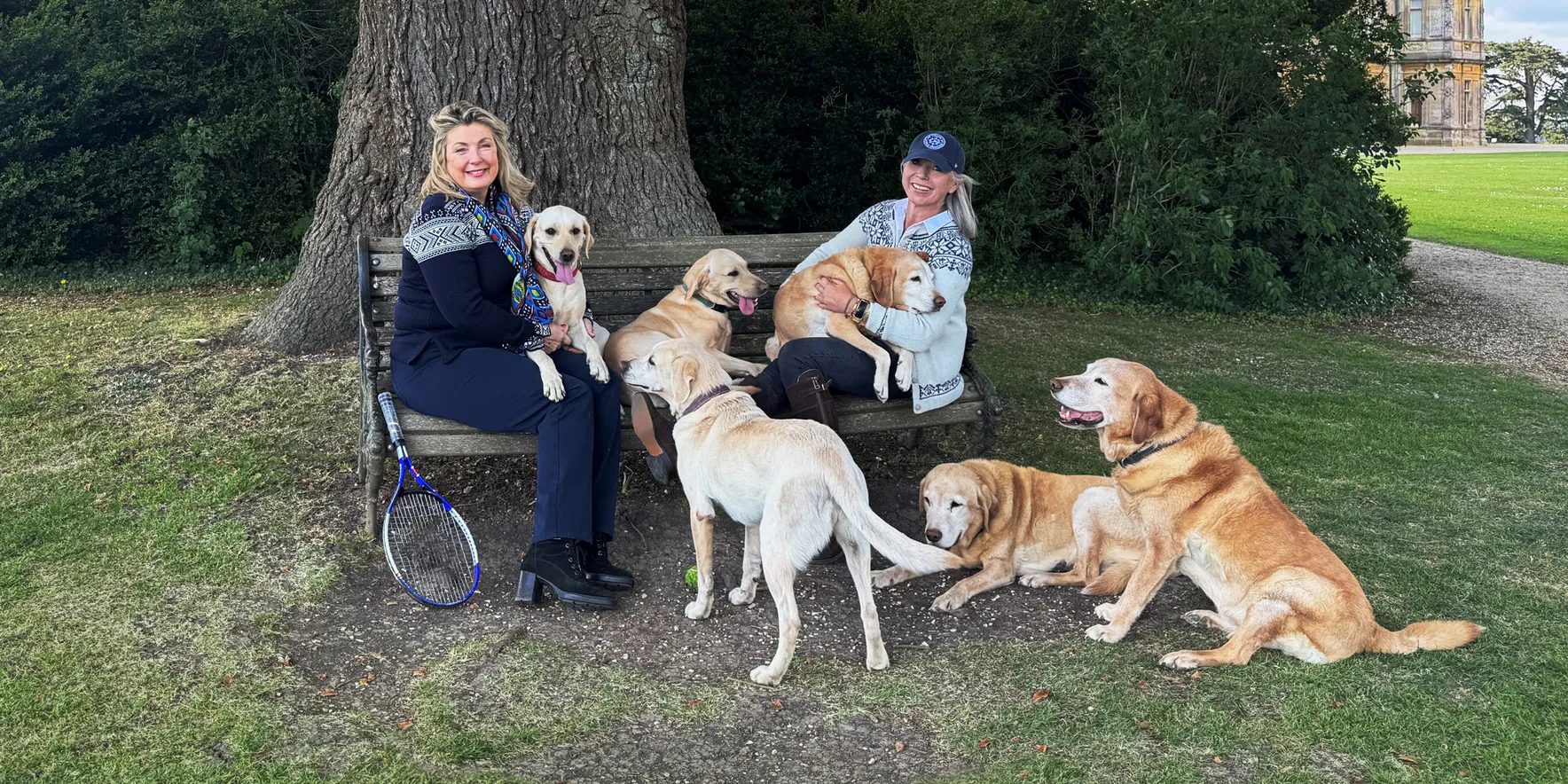 Two women with dogs under a large tree